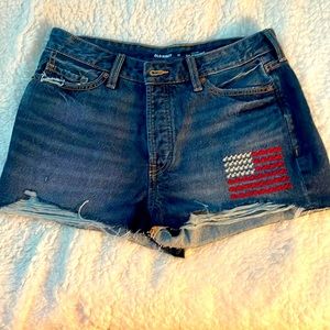 Dark jean shorts with embroidered flag.